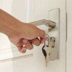 Hand_use_the_key_for_unlocking_and_open_the_white_door