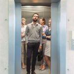 Confident_business_people_standing_in_elevator_at_office