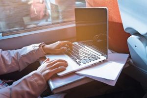 Close_up_of_young_woman_traveling_by_train_and_working_on_laptop._Business_travel_concept.