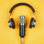 podcasting_concept,_directly_above_view_of_headphones_and_recording_microphone_on_orange_background