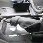 Worker_in_isolated_black_rubber_gloves_cleans_staple_printing_platform_inside_of_3d_printer_for_metal._Person_in_gloves_cleans_metal_powder_inside_industrial_machine._Laser_sintering_machine_for_metal