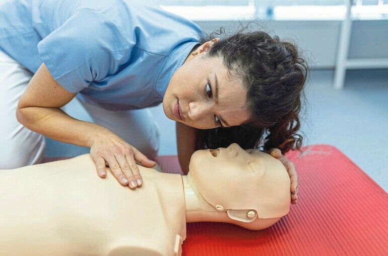 CPR_class_with_instructors_talking_and_demonstrating_firt_aid,_compressions_ans_reanimation_procedure._Cpr_dummy
