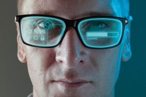 A_close_up_image_of_a_man_wearing_smart_arugmented_reality_glasses_with_virtual_screen_displaying_icons_and_loading_screen_-_modern_technology_concept_image_with_copy_space_for_text.