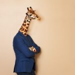 Portrait_of_giraffe_headed_businessman,_wearing_blue_suit_with_his_arms_folded,_leaning_at_blanked_space_for_copy,_concept_of_office_worker
