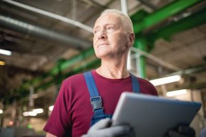 Senior_worker_with_modern_gadget_thinking_of_which_method_of_industrial_processing_to_search_in_the_net