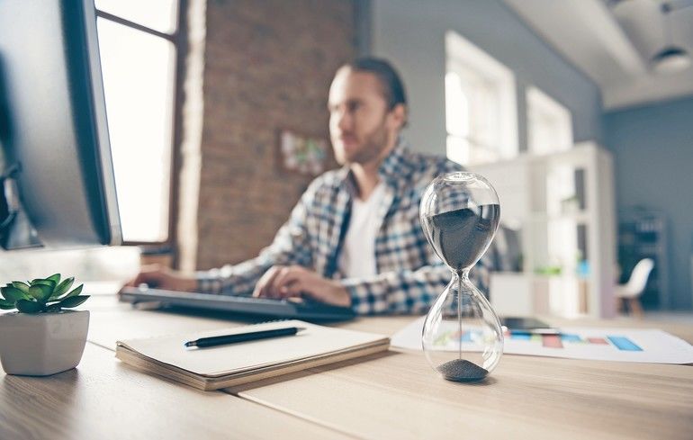 Blurry_focus_photo_of_handsome_business_guy_look_computer_monitor_sand_clock_on_table_chatting_boss_promise_finish_report_in_time_wear,_casual_shirt_suit_sitting_chair_office_indoors