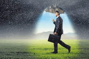 Young_businessman_with_umbrella_under_rain_walking_on_field