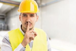 Factory_or_company_engineer_making_shush_silence_gesture_with_index_finger_on_lips
