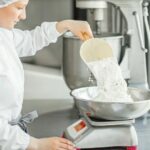 Woman_confectioner_in_uniform_weighing_ingredients_for_pastry_working_at_the_bakery_manufacturing
