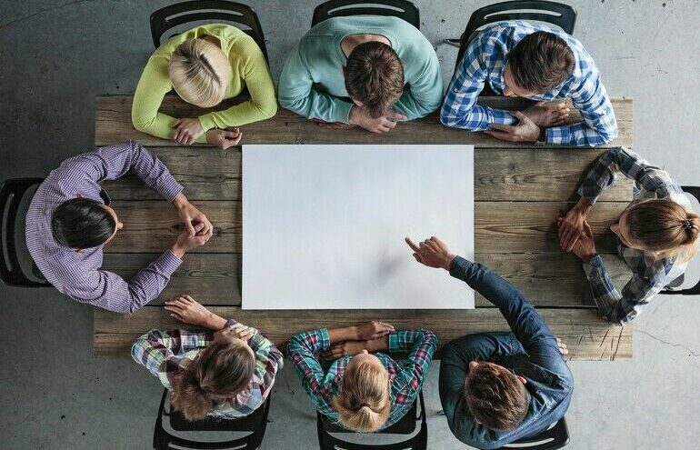 Hipster_business_teamwork_brainstorming_planning_meeting_concept,_people_sitting_around_the_table_with_white_paper