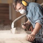 Horizontal_view_of_professionally_dressed_carpenter_varnishing_a_board