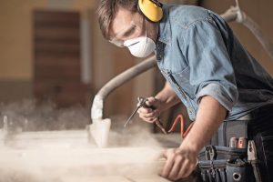 Horizontal_view_of_professionally_dressed_carpenter_varnishing_a_board